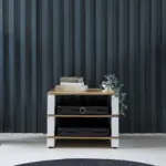 Blok Stax 2G White dark panelled wall Stax 2G Base and two shelves in natural ash and satin white, holding electronics against a dark panelled wall
