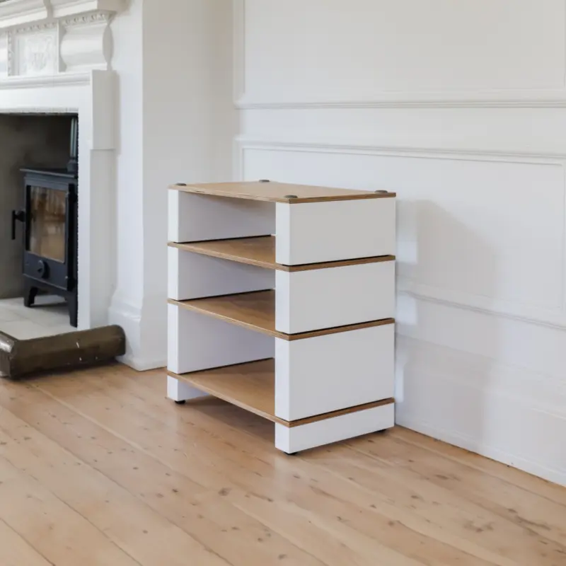 Stax 2G Base carrying three shelves in natural ash and satin white beside a fireplace